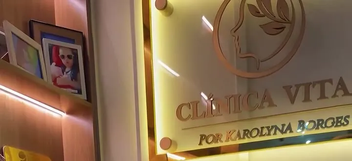 Letreiro dourado “Clínica Vitae por Karolyna Borges” iluminado no consultório